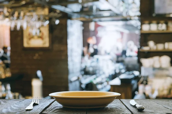 Пустая тарелка с вилкой и ножом на деревянном столе — стоковое фото