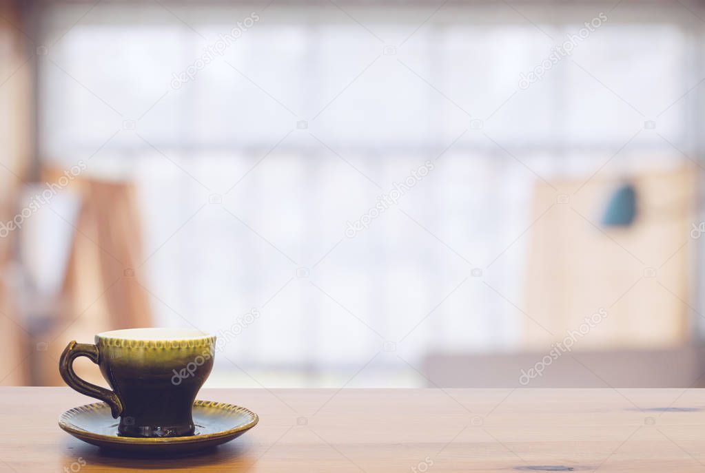 green cup on wooden table with blurred interior on background