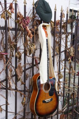 Gitar, tepe-kap ve eşarp bir çitin üzerine asmak