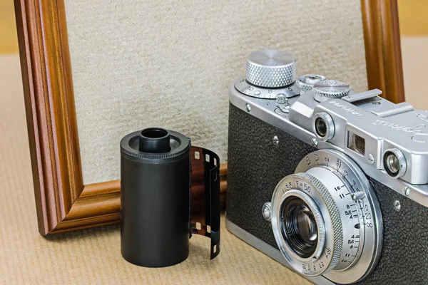 retro camera, film roll and empty wooden photo frame in vintage style
