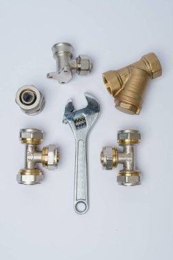 Beyaz zemin üzerinde bir İngiliz anahtarı ve metal bağlantı parçaları ile ayarla