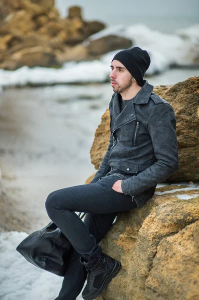 Knappe jonge man op het strand op de rotsen — Stockfoto
