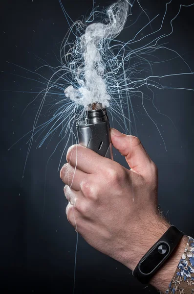 Mano sosteniendo un cigarrillo electrónico sobre un fondo oscuro —  Fotos de Stock