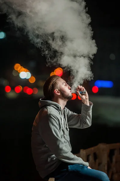 Pohledný mladý muž kouření elektronické cigarety — Stock fotografie