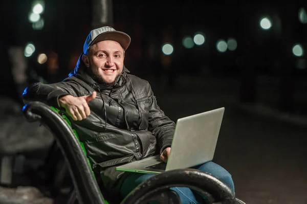 Przystojny, młody człowiek z komputerem na ławce w parku — Zdjęcie stockowe