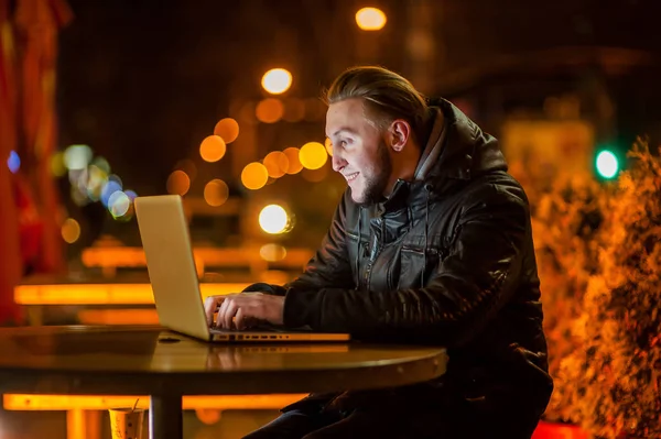 Knappe jonge man met een computer in de straat — Stockfoto