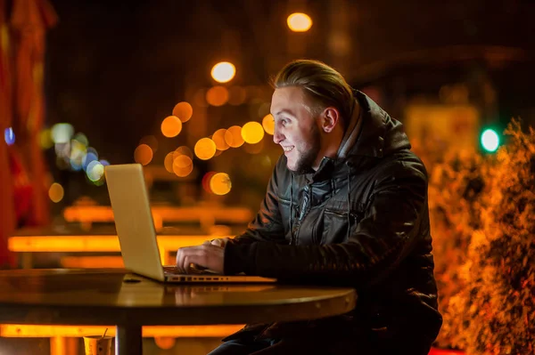 Knappe jonge man met een computer in de straat — Stockfoto
