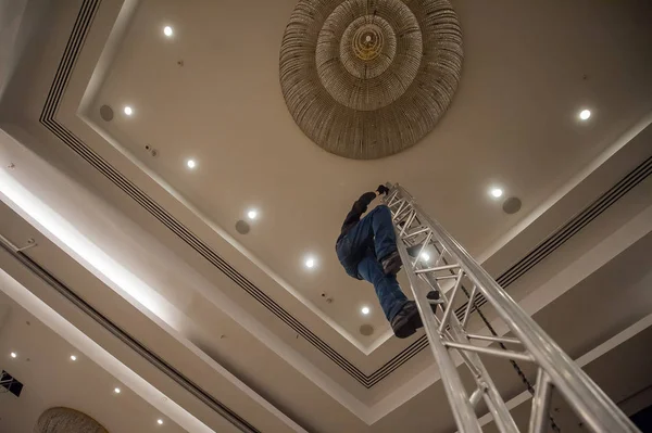 Homem trabalha em uma escada de metal — Fotografia de Stock