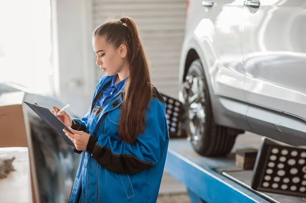 Joven hermosa chica en un mecánico de automóviles en el trabajo — Foto de Stock