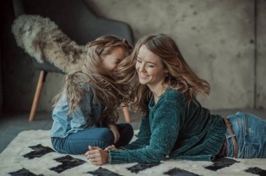 Anne ile kızı odasında halı üzerinde gülümseyen