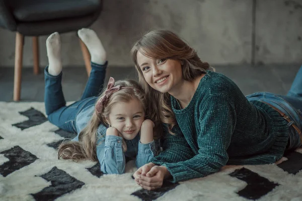 Sonriente madre con su hija en la habitación de la alfombra —  Fotos de Stock