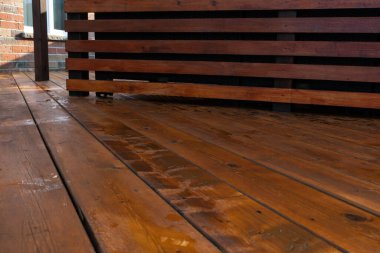 Arka bahçe ahşap döşeme tahtaları taze kahverengi lekeli, açılı manzaralı.