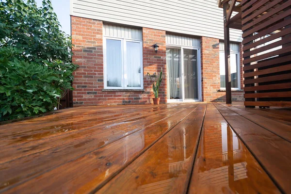 Backyard wooden deck floor boards with fresh brown stain, angled view