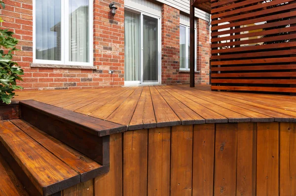 Backyard wooden deck floor boards with fresh brown stain, angled view