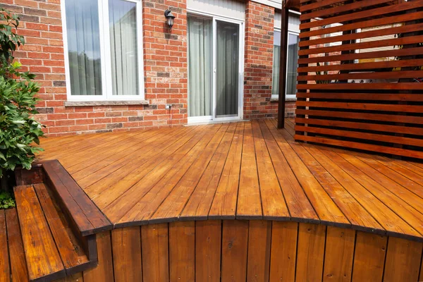 Backyard wooden deck floor boards with fresh brown stain, angled view