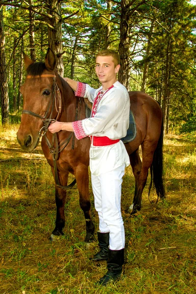 Young Ukrainian with a horse in the forest — Stock Photo, Image