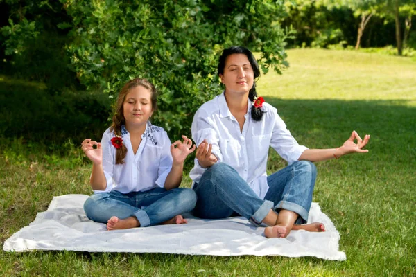 Anne ve kızı çimlere oturup meditasyon — Stok fotoğraf