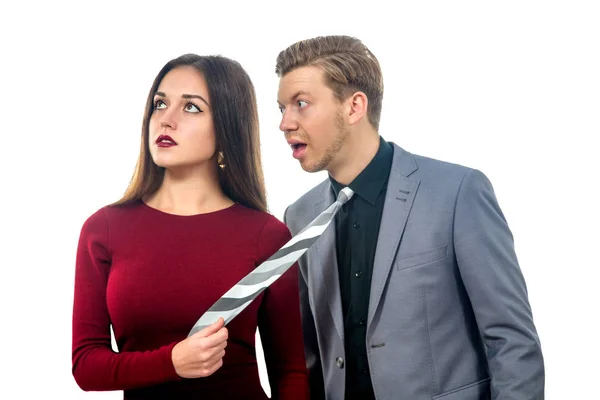 Girl in a red dress pulling man by tie — Stock Photo, Image