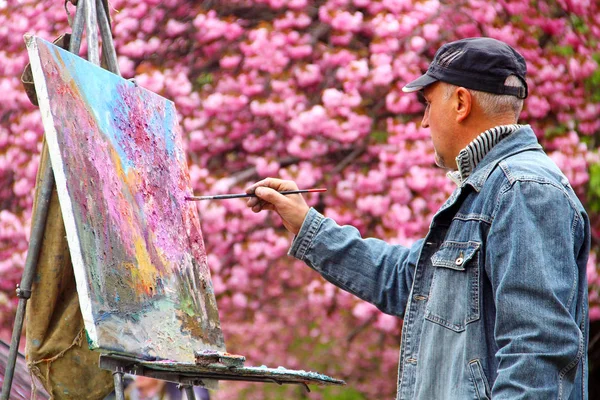 An artist paints a picture of blooming sakura — Stock Photo, Image