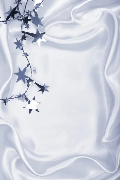 Estrelas de prata e lantejoulas em seda branca tonificada como fundo — Fotografia de Stock