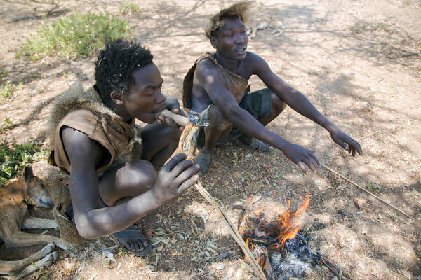 Two Hazabe bushman of the hadza tribe smokes a traditional pipe