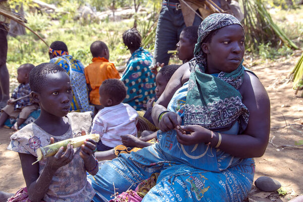 Portrait woman with a baby who eats sugarcane of the Hadzabe tribe