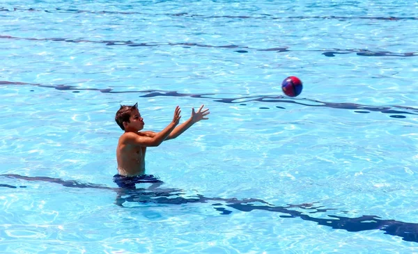 Jeune garçon sportif jouant au ballon dans une grande piscine extérieure — Photo