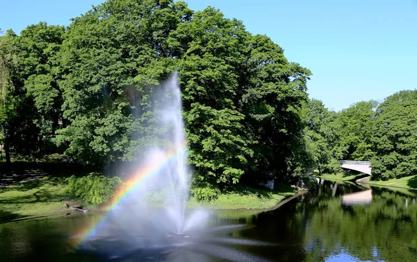 Fountain with a rainbow in Riga river canal — Stock Photo, Image