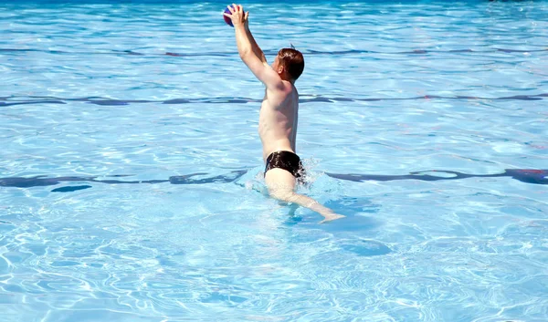 Hombre activo jugando pelota en una gran piscina al aire libre — Foto de Stock