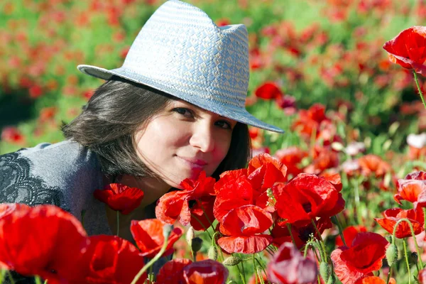 Menina encantadora em um chapéu de verão contra um fundo de papoilas vermelhas — Fotografia de Stock