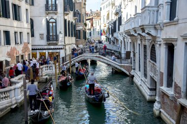 Venice, İtalya - 16 Eylül 2017: Gondol Venedik, İtalya için birden çok küçük köprüler altında bir kanal boyunca yelken. Yaz Venedik'te seyahat ve tatil kavramı. Şehir her yıl yaklaşık 30 milyon kişi ziyaret.