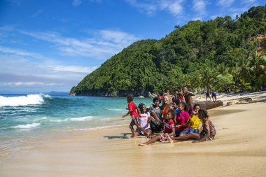 PAPUA NEW GUINEA, JAYAPURA, AUGust, 15, 2019 - Endonezyalı komik çocuklar Sentani, Jayapura, Yeni Gine 'deki Pantai Üssü plajında beyaz bir bayanla fotoğraflandı.