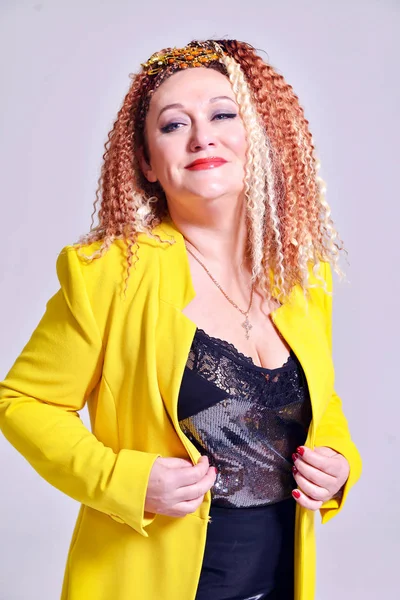 Attractive Smiling Woman Curly Hair Yellow Jacket Posing Studio — Stock Photo, Image