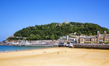 İspanya, San Sebastian, 12 Mayıs 2018 - La Concha plajı Urgul Dağı manzaralı - tepesinde ortaçağ La Mota kalesi ve bir İsa heykeli bulunuyor. San Sebastian, Donostia, İspanya