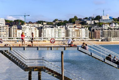 İspanya, SAN SEBASTIAN, MAYIS, 10, 2018 - İnsanlar metal köprülerde oturuyor ve Atlantik Okyanusu 'nun Playa de La Concha sahilindeki gelgitinin tadını çıkarıyorlar, San Sebastian, Donostia, İspanya