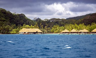 Lüks Klasik thatched çatı bungalow resort Bora Bora, Fransız Polinezyası gündoğumu ışınları içinde ahşap bir duba üzerinde.
