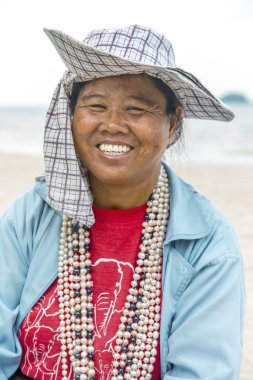 THAILAND, KOH CHANG, Mart 2016 - Tayland 'ın Koh Chang adasındaki sahilde pamuk şapkalı gülümseyen Taylandlı kadın inci satıyor