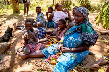 AFRİKA, TANZANIA, 10 Mayıs 2016 - Hadzabe kabilesinin çocukları yerde oturan kadın. Hadzabe kabilesi Tanzanya, Afrika 'da yok olma tehlikesiyle karşı karşıya.