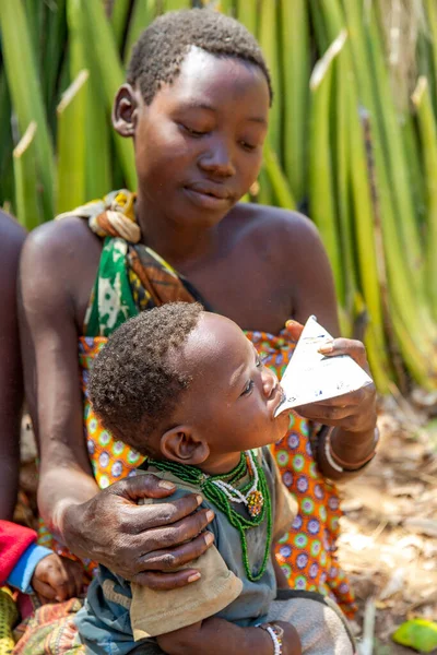 Tanzania May 2016年5月10日 Hadzabe部落有小孩的妇女从包装中喂养婴儿奶 — 图库照片