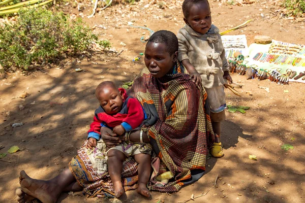 AFRİKA, TANZANIA, 10 Mayıs 2016 - Hadzabe kabilesinin küçük çocukları yerde oturan kadın. Hadzabe kabilesi Tanzanya, Afrika 'da yok olma tehlikesiyle karşı karşıya.
