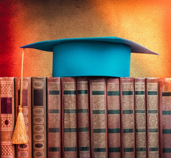 Graduation mortarboard sur le dessus de la pile de livres sur le dos abstrait — Photo