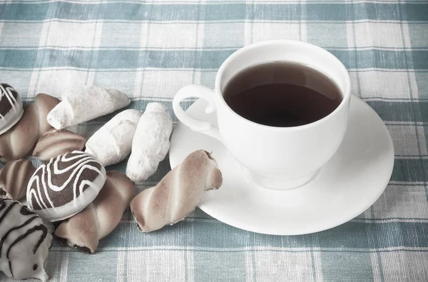 Taza de té y deliciosas galletas en mantel a cuadros azul — Foto de Stock