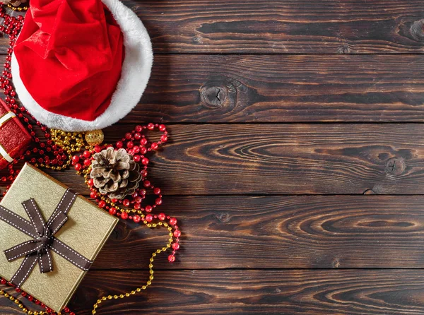 Geschenkschachteln mit Perlen, Spielzeug und Weihnachtsmann-Hut auf einem Holztisch — Stockfoto