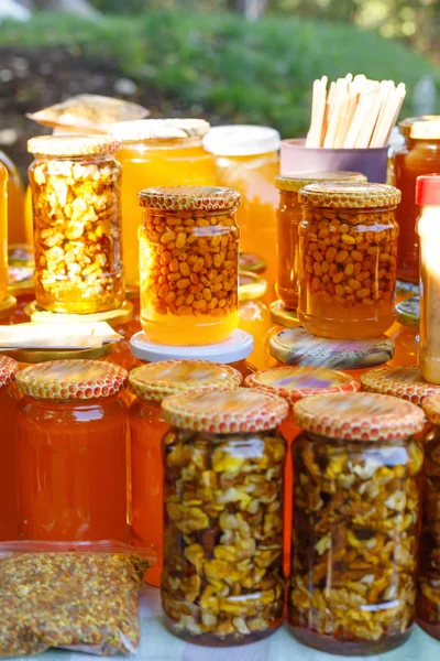 Sortiment medových nádob v prodejně. Prodej přírodního medu na veletrhu venkovní. — Stock fotografie