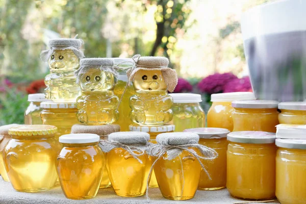 Frascos y palitos de miel con miel natural en el estante en feria. Venta de miel natural en el mercado exterior . — Foto de Stock