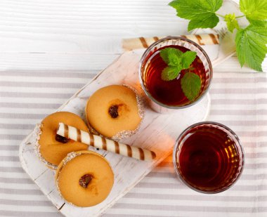 Beyaz ahşap masada lezzetli kurabiyelerle iki fincan sıcak çay.