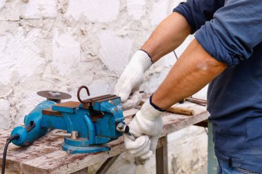 İşçi, evin arka bahçesinde elektrikli aletler, çekiç ve kerpetenle tamirat yapıyor..