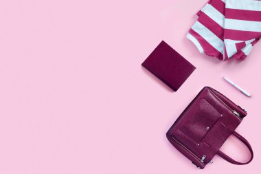 Kadınların deri çantaları, not defterleri ve pembe kağıt arka plandaki kalemler için güzel yün kazaklar. Üst görünüm düzlüğü, boşluk konseptini kopyala.