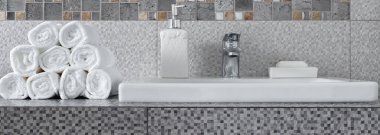 Modern banyodaki seramik tezgahta bir yığın temiz beyaz havlu.