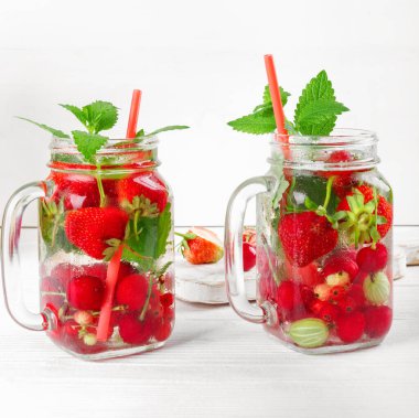 Taze taze meyve suyu, çilek, frenk üzümü ve Bektaşi üzümü beyaz ahşap masada.